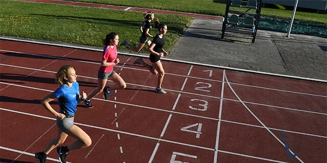 Vier hardloopsters voor de finish op een atletiek baan